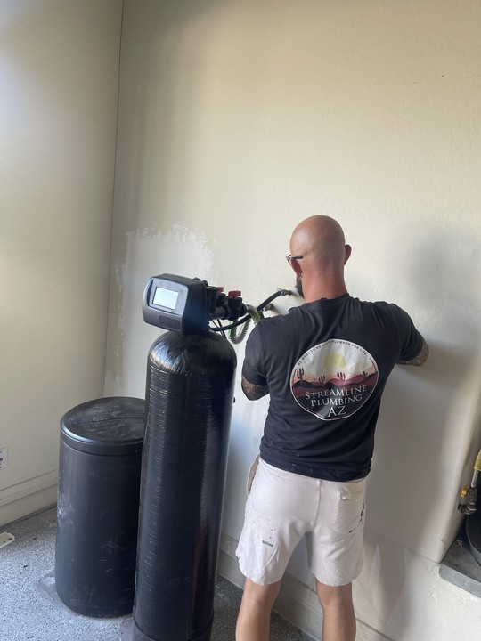 A plumber working on a burst pipe with water spraying.